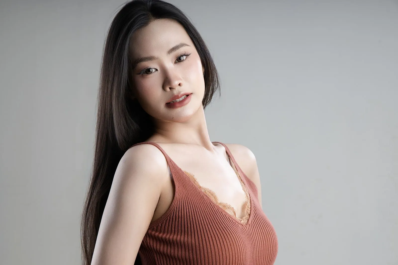 Cô gái áo hai dây màu đất nung nghiêng đầu nhìn máy, ảnh cho nội dung mạng xã hội